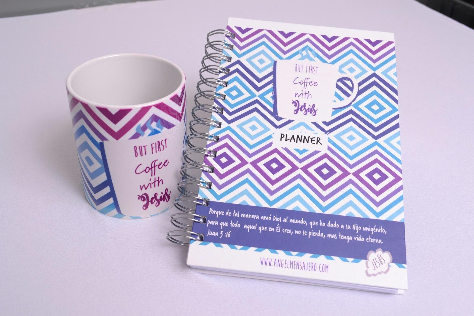 A cup of coffee next to a planner on a table