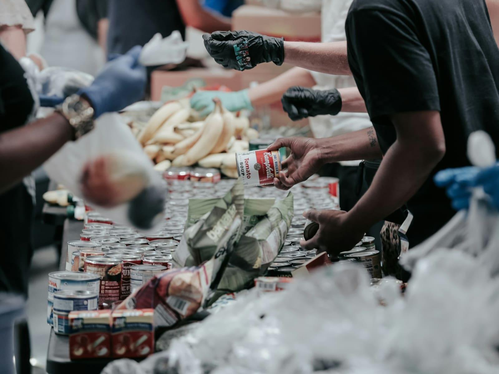 Volunteers sorting cans and fresh produce on a long donation table