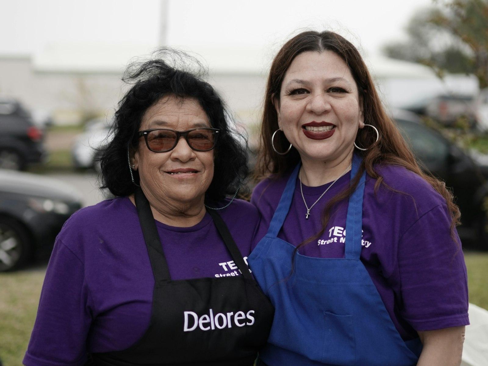 Volunteers in aprons at a community fundraising event outdoors