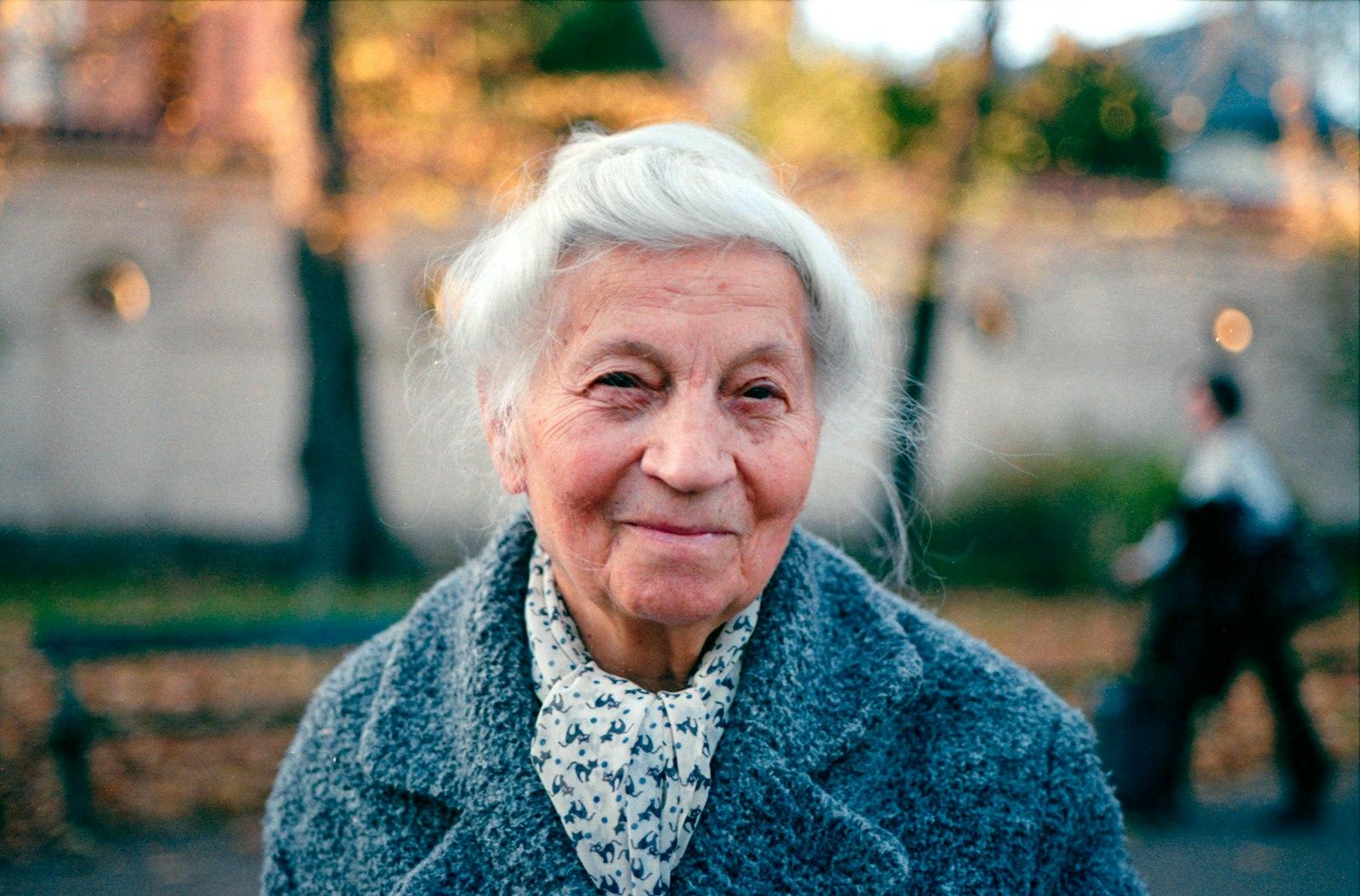 A grandmother in a grey coat smiling at the camera